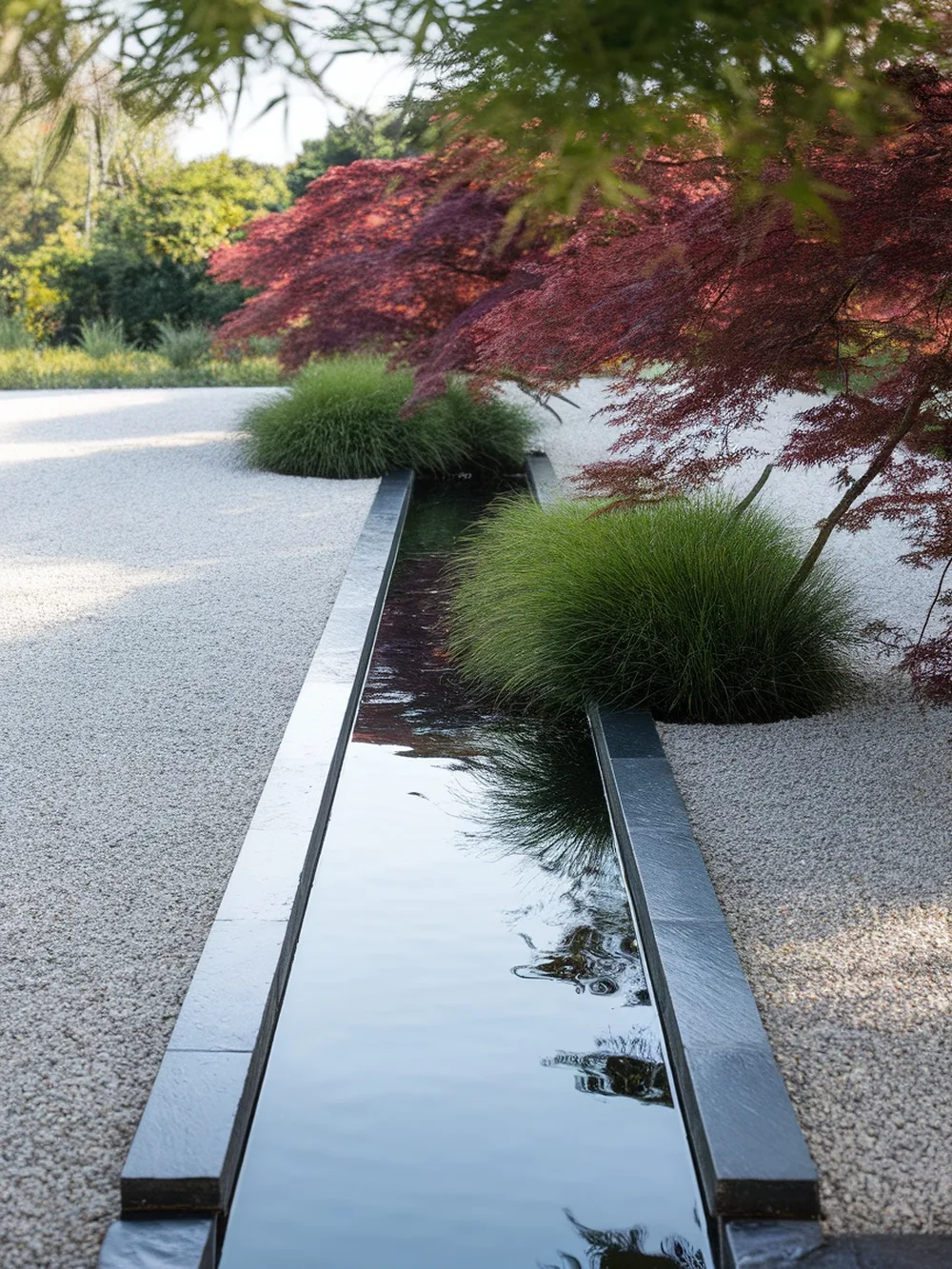 A gravel garden featuring a sleek water runnel surrounded by green plants.